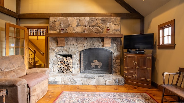 living room featuring wood-type flooring, lofted ceiling, and a stone fireplace