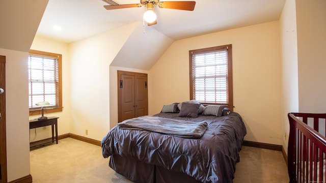 carpeted bedroom featuring ceiling fan, lofted ceiling, a closet, and multiple windows