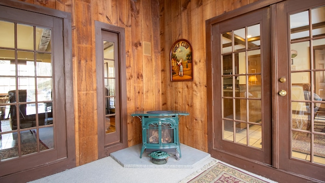 doorway to outside with wooden walls, french doors, and a wood stove