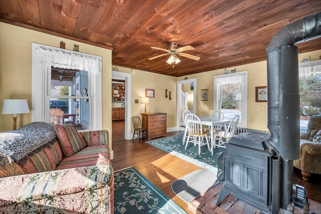 living room with ceiling fan, a wood stove, dark wood-type flooring, and wood ceiling