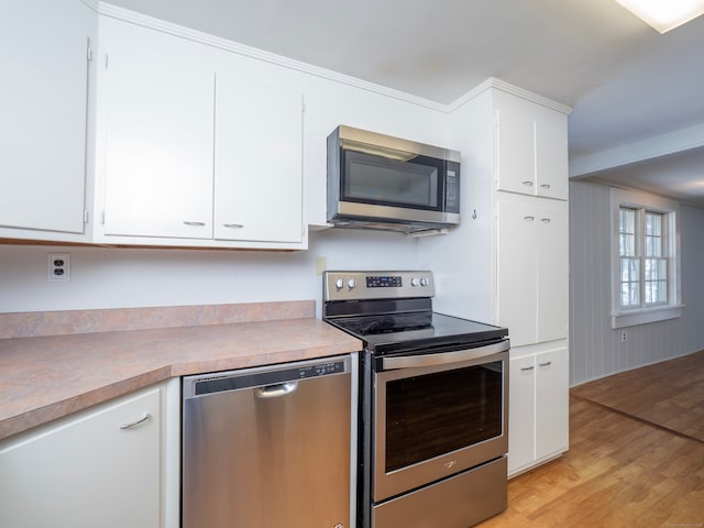 kitchen with appliances with stainless steel finishes, white cabinets, and light wood-type flooring