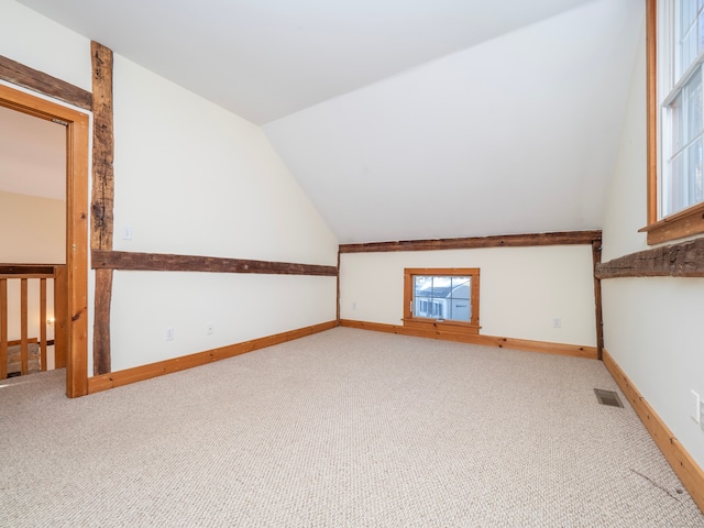 bonus room with vaulted ceiling and light carpet