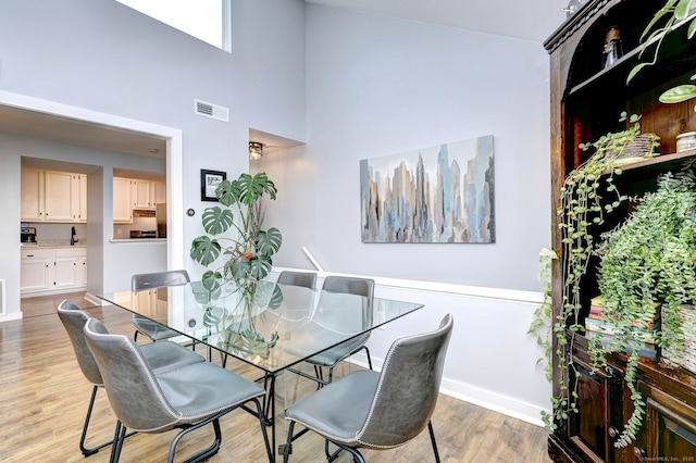 dining space featuring light hardwood / wood-style floors and a high ceiling