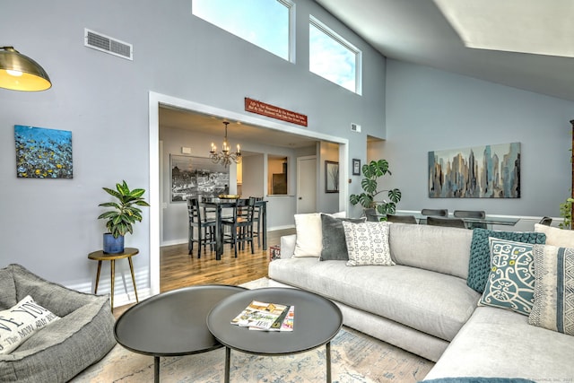 living room featuring high vaulted ceiling, hardwood / wood-style flooring, and an inviting chandelier