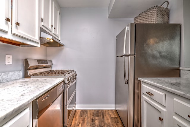 kitchen with light stone countertops, white cabinetry, appliances with stainless steel finishes, and dark wood-type flooring