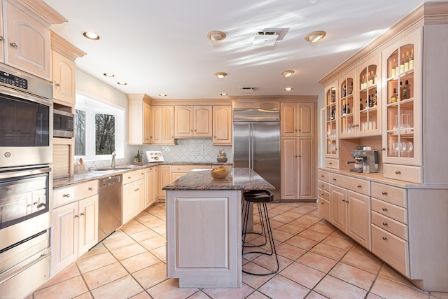 kitchen featuring stainless steel appliances, a center island, a kitchen bar, and light tile patterned flooring