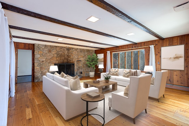 living room featuring a baseboard radiator, light hardwood / wood-style flooring, beam ceiling, and a fireplace