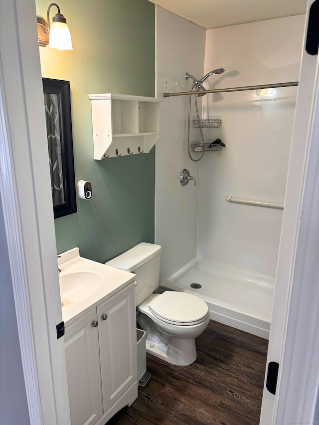 bathroom with wood-type flooring, a shower, vanity, and toilet