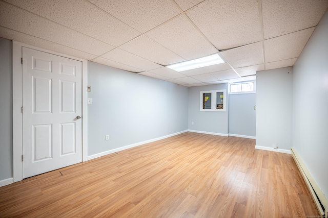 basement with wood-type flooring, a drop ceiling, and a baseboard radiator