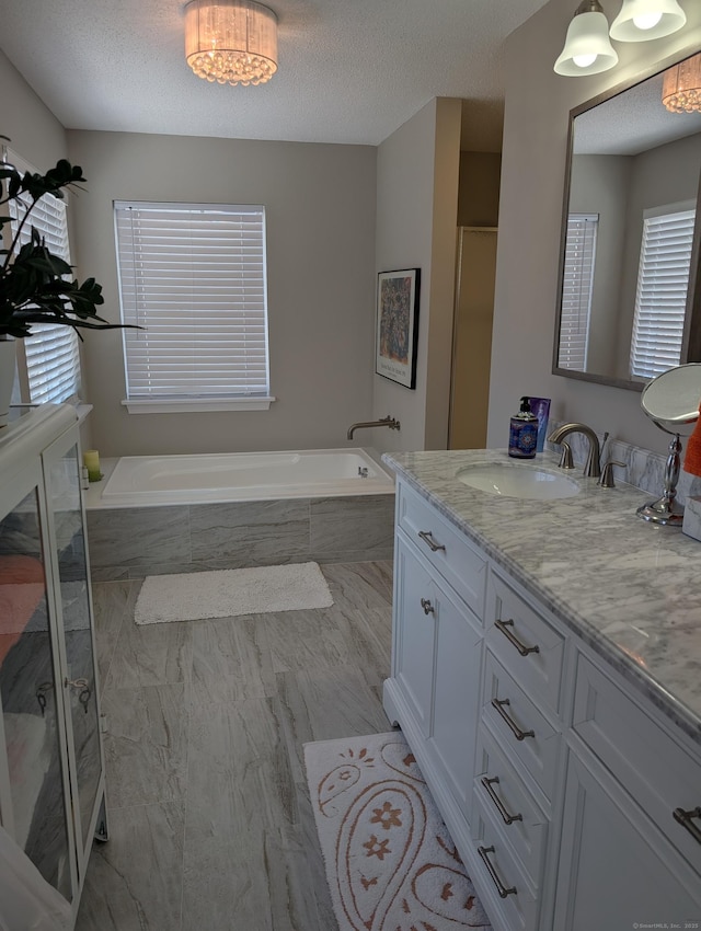 bathroom featuring vanity, plus walk in shower, and a textured ceiling