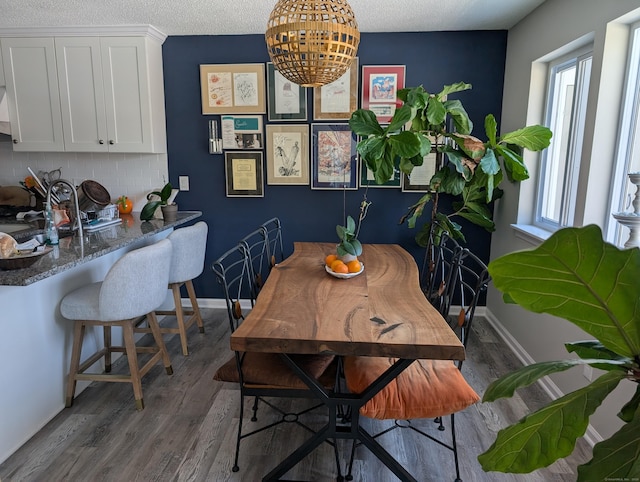 dining room with dark wood-type flooring, plenty of natural light, and a textured ceiling