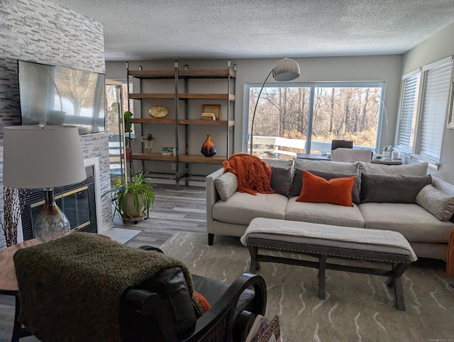 living room featuring wood-type flooring, a fireplace, and a textured ceiling