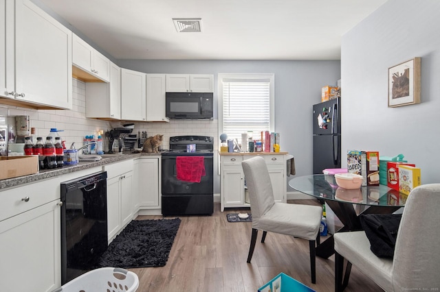 kitchen with backsplash, black appliances, white cabinets, and light hardwood / wood-style floors