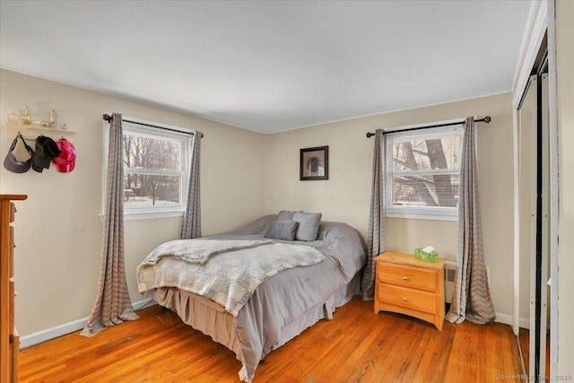 bedroom with multiple windows, light hardwood / wood-style floors, and a closet