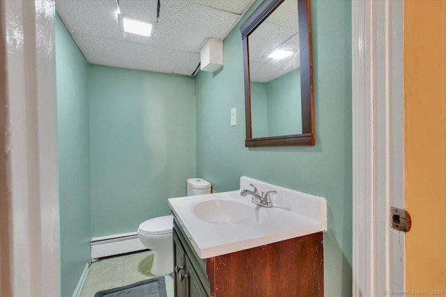 bathroom featuring vanity, a baseboard heating unit, toilet, a drop ceiling, and tile patterned floors