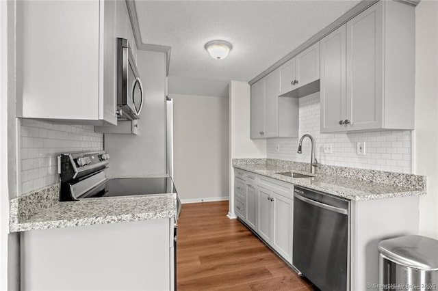 kitchen with light stone counters, sink, light hardwood / wood-style flooring, and stainless steel appliances