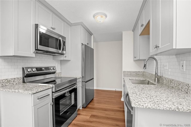 kitchen featuring light hardwood / wood-style floors, appliances with stainless steel finishes, light stone countertops, and sink