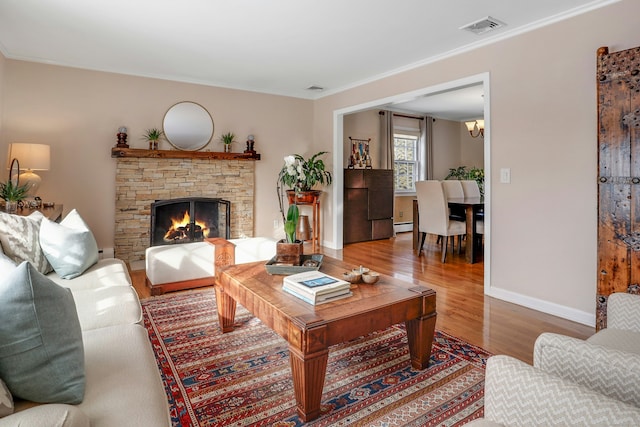 living room featuring wood-type flooring, a stone fireplace, crown molding, and a baseboard radiator