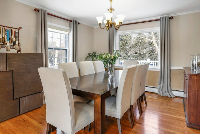 dining space with crown molding, a notable chandelier, and light hardwood / wood-style flooring