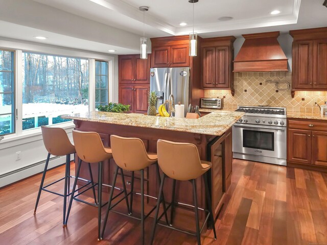 kitchen featuring a breakfast bar area, stainless steel appliances, custom range hood, and a kitchen island