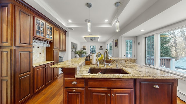 kitchen featuring sink, crown molding, hanging light fixtures, light stone countertops, and light wood-type flooring