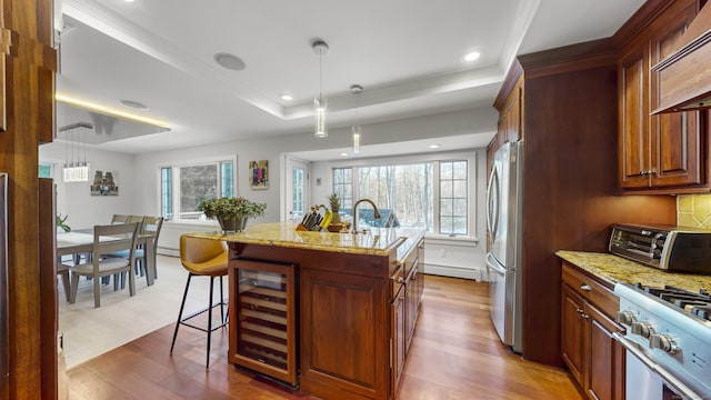 kitchen featuring a kitchen bar, light stone counters, appliances with stainless steel finishes, beverage cooler, and a kitchen island with sink