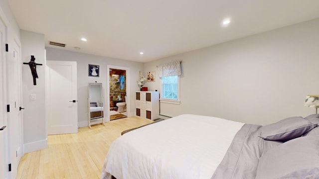 bedroom with ensuite bath, a baseboard radiator, and light hardwood / wood-style flooring