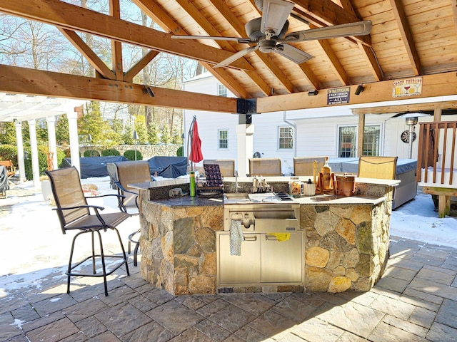 view of patio with a bar, a gazebo, ceiling fan, and an outdoor kitchen