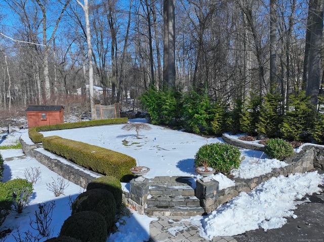 yard layered in snow featuring a storage shed