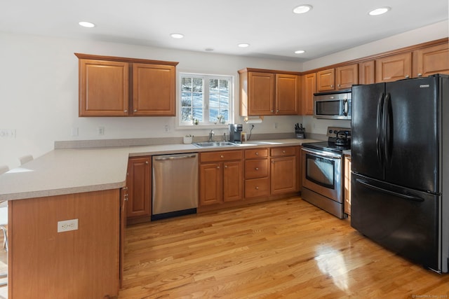 kitchen featuring sink, appliances with stainless steel finishes, light hardwood / wood-style flooring, and kitchen peninsula