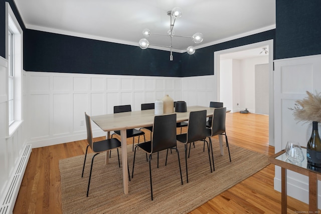 dining space with hardwood / wood-style flooring, a wealth of natural light, and a baseboard heating unit