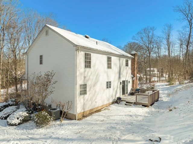 view of snowy exterior featuring a wooden deck and central AC