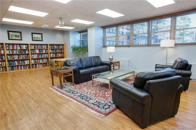 living room featuring a drop ceiling and light hardwood / wood-style flooring