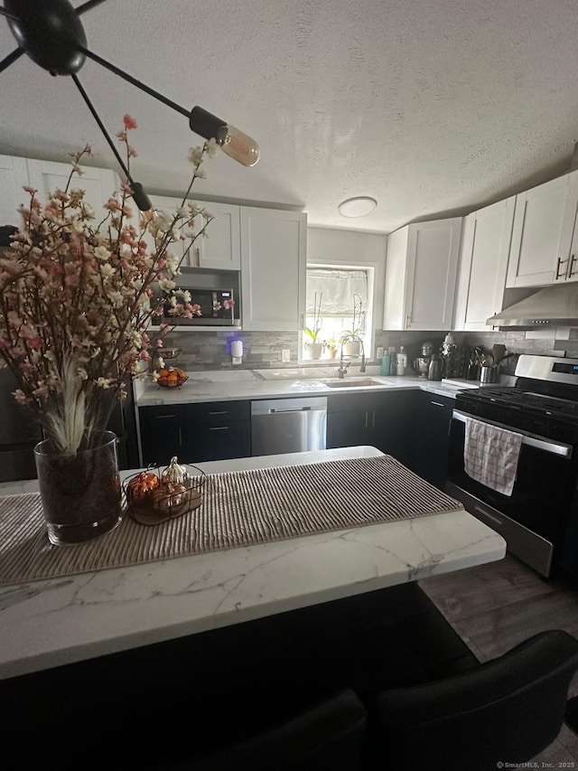 kitchen with stainless steel appliances, sink, a textured ceiling, and white cabinets