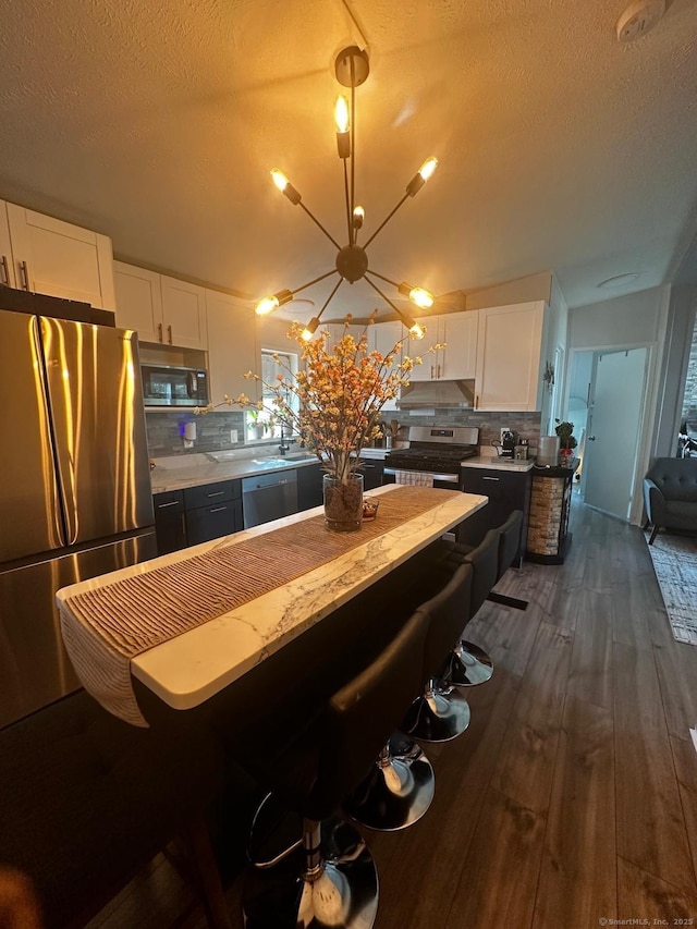 kitchen featuring dark hardwood / wood-style flooring, decorative backsplash, stainless steel appliances, and white cabinets