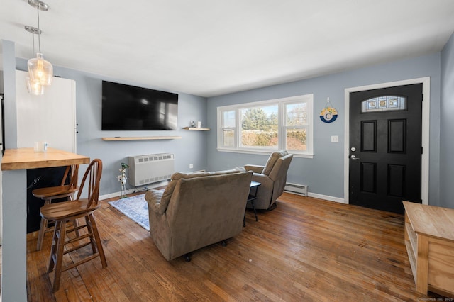 living room featuring wood-type flooring, a baseboard radiator, and heating unit