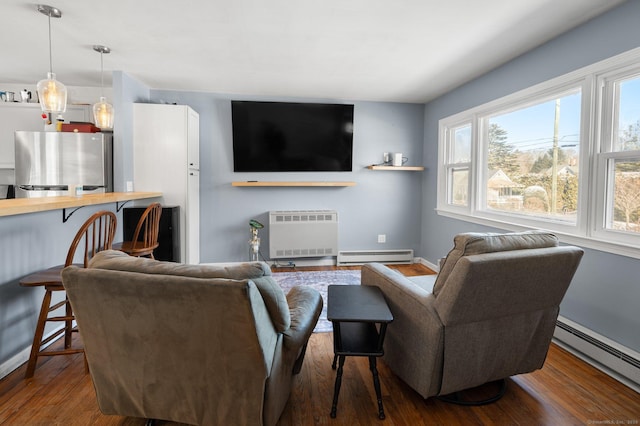 living room with heating unit, a baseboard heating unit, and hardwood / wood-style floors