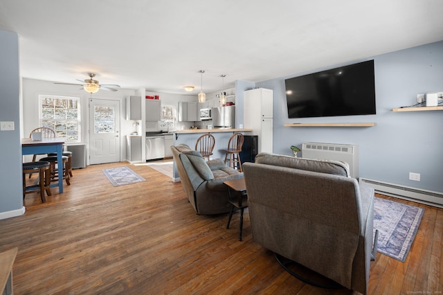 living room with radiator heating unit, hardwood / wood-style floors, baseboard heating, sink, and ceiling fan