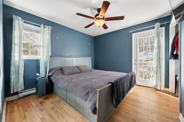 bedroom with light hardwood / wood-style floors, ceiling fan, and baseboard heating