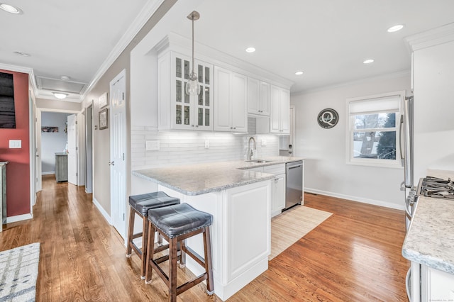 63 Contact Dr, West Haven, CT 06516 - kitchen featuring ornamental molding, a peninsula, white cabinetry, a sink, and appliances with stainless steel finishes