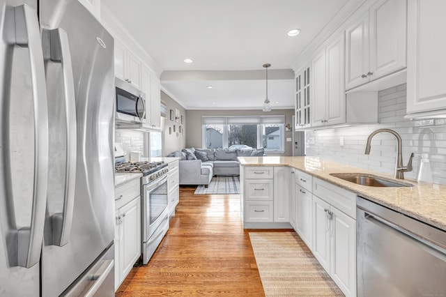 63 Contact Dr, West Haven, CT 06516 - kitchen featuring white cabinets, appliances with stainless steel finishes, a sink, light wood finished floors, and open floor plan