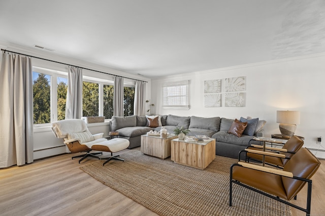 living room with ornamental molding, a baseboard heating unit, and light wood-type flooring