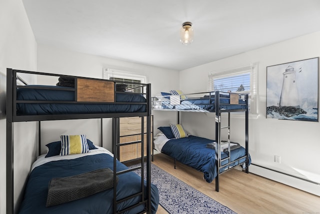 bedroom featuring a baseboard heating unit and wood-type flooring