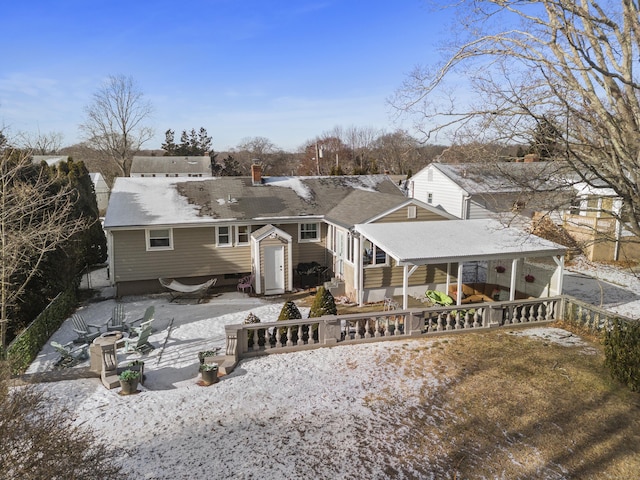 snow covered back of property with an outdoor fire pit