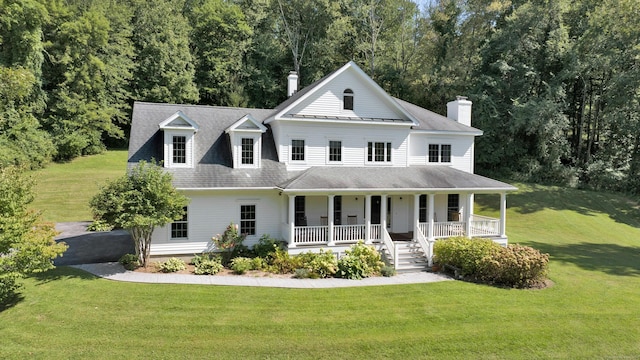 view of front facade with covered porch, a forest view, and a front lawn