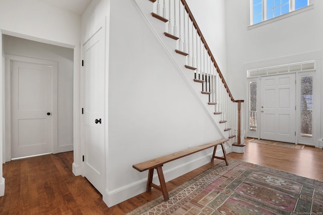 foyer entrance with stairs, a high ceiling, baseboards, and wood finished floors