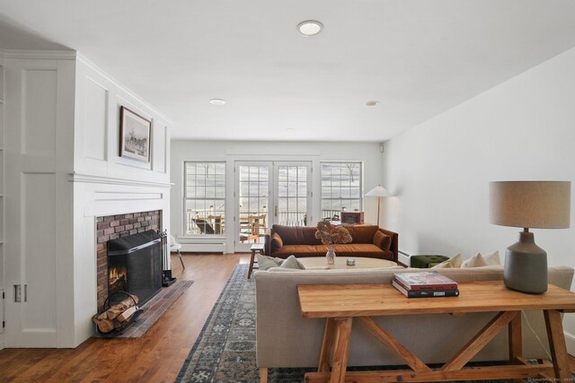 living room with a brick fireplace, french doors, recessed lighting, and wood finished floors