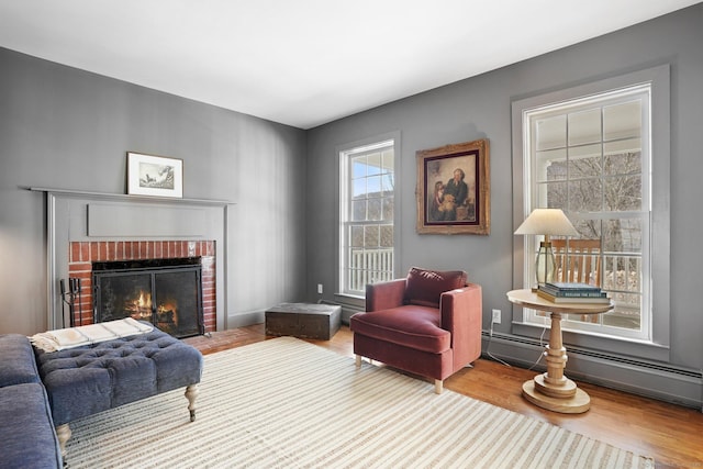 living area featuring a baseboard heating unit, a fireplace, and wood finished floors