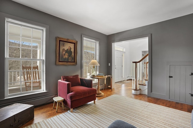 sitting room featuring stairs, a baseboard radiator, and wood finished floors