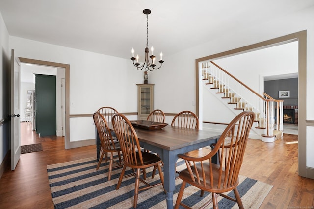 dining area featuring a chandelier, stairway, light wood-type flooring, and a fireplace